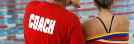 Coach and swimmer standing by pool