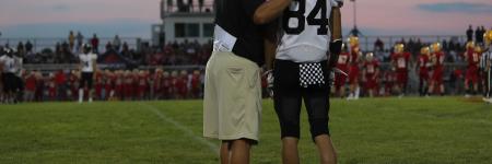 football coach and football player on a football field looking at the stands