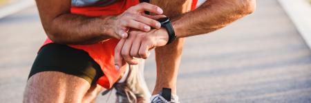 a runner crouched down, looking at his watch