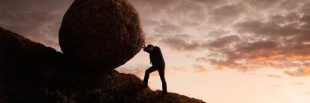 a person pushing a boulder uphill