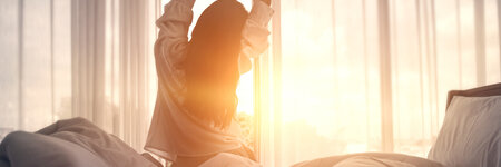 a woman is stretching in her bed at sunrise