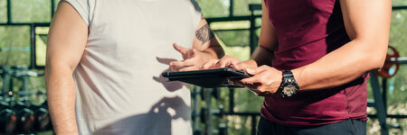 close-up of two guys' torsos who are having a conversation with one guy holding a clipboard 